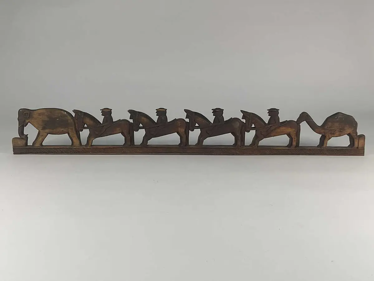 A carved wooden frieze depicting figures riding horses...