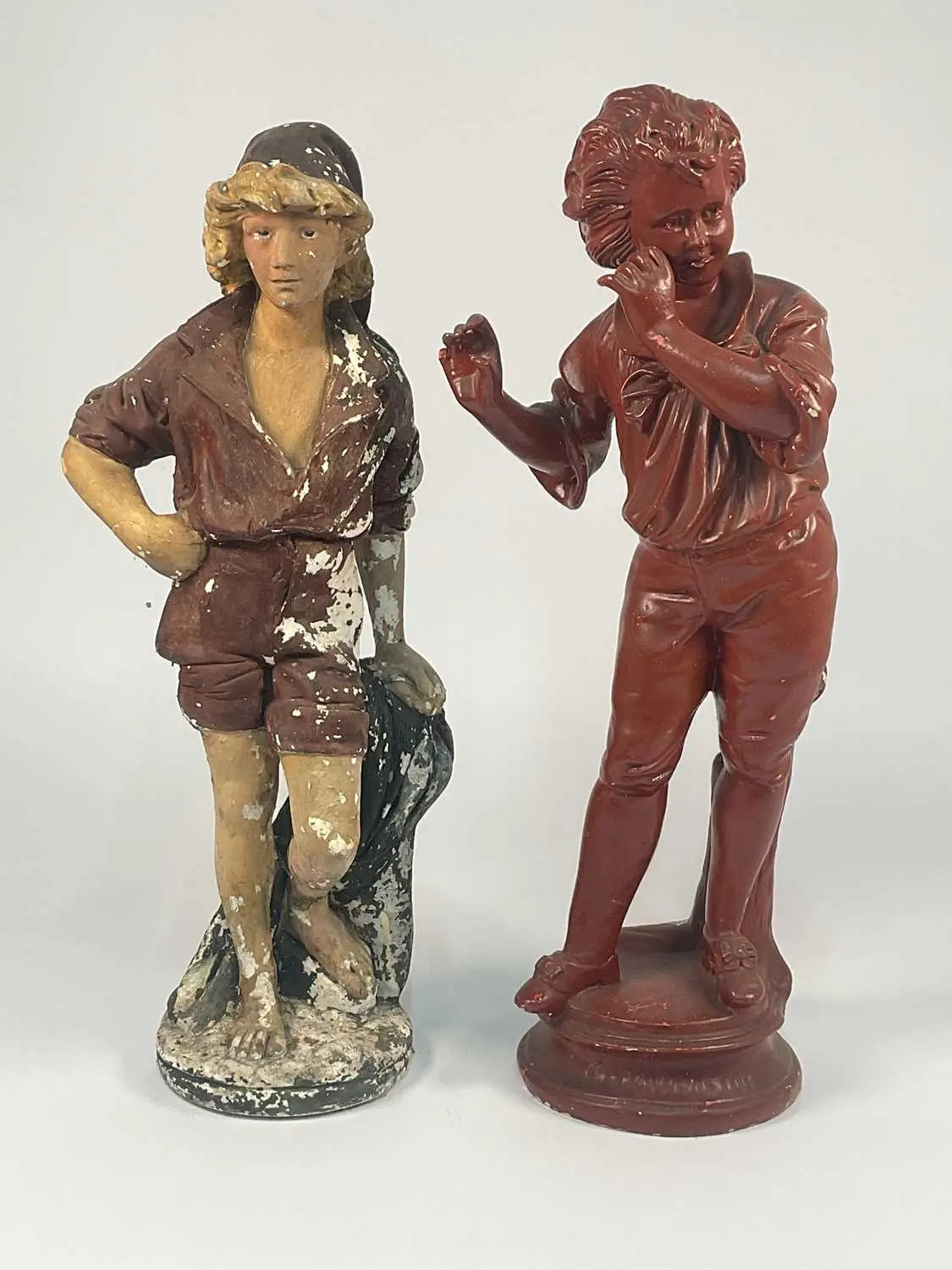 A large painted chalk ware figure of a boy in a cap