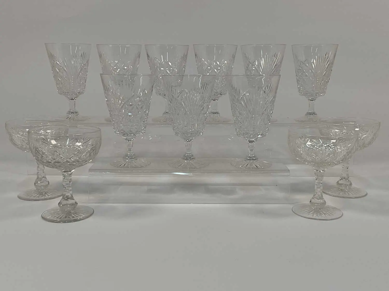 A quantity of cut crystal champagne coupes and wine glasses