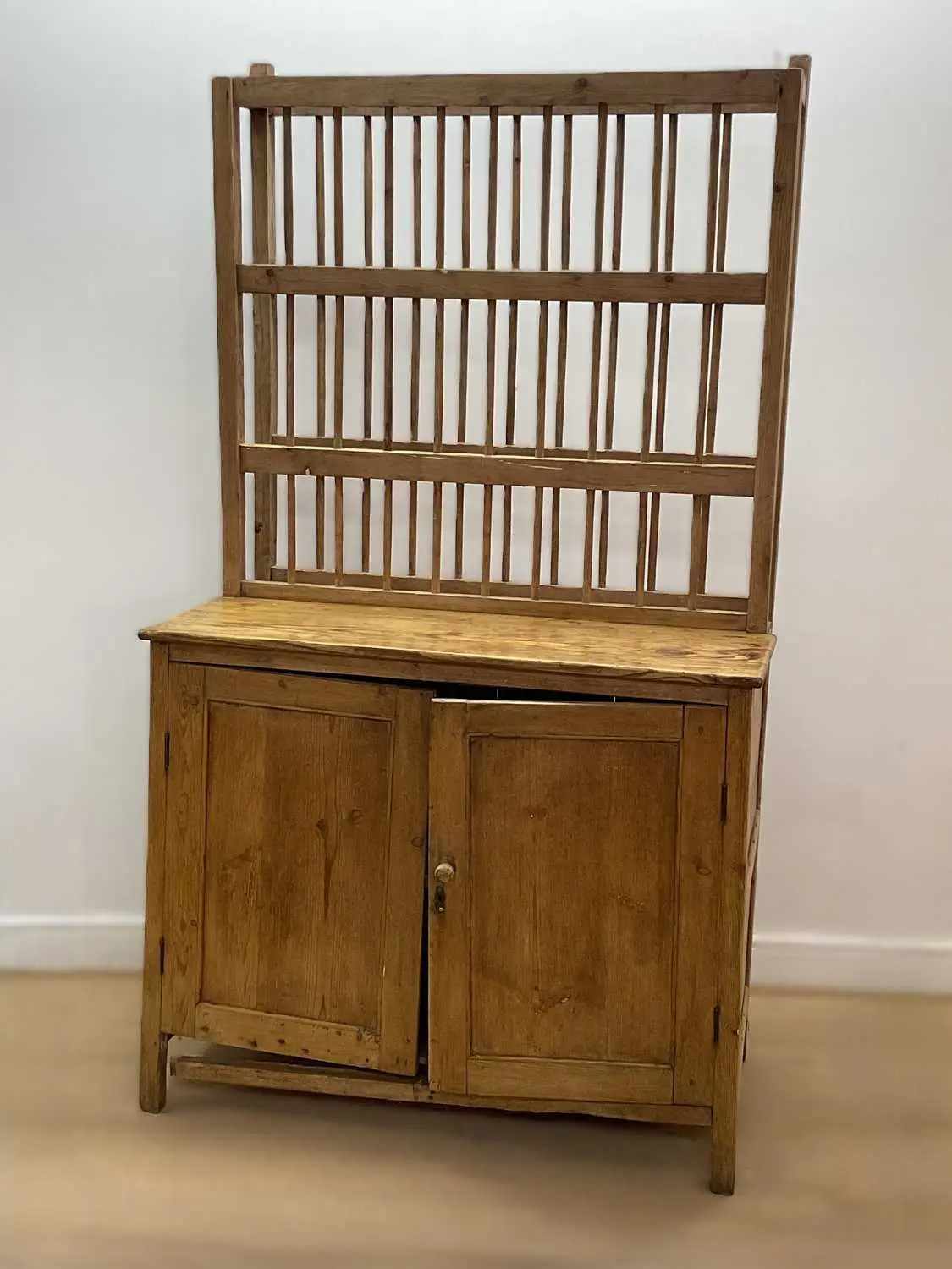 A pine kitchen dresser with spindle back plate rack and cupboard beneath