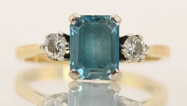 An 18ct yellow gold blue zircon and diamond set three stone ring