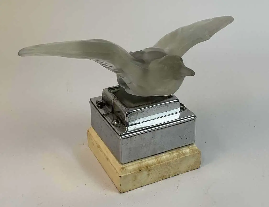 A glass bird hood ornament / car mascot mounted on a chrome and wooden plinth