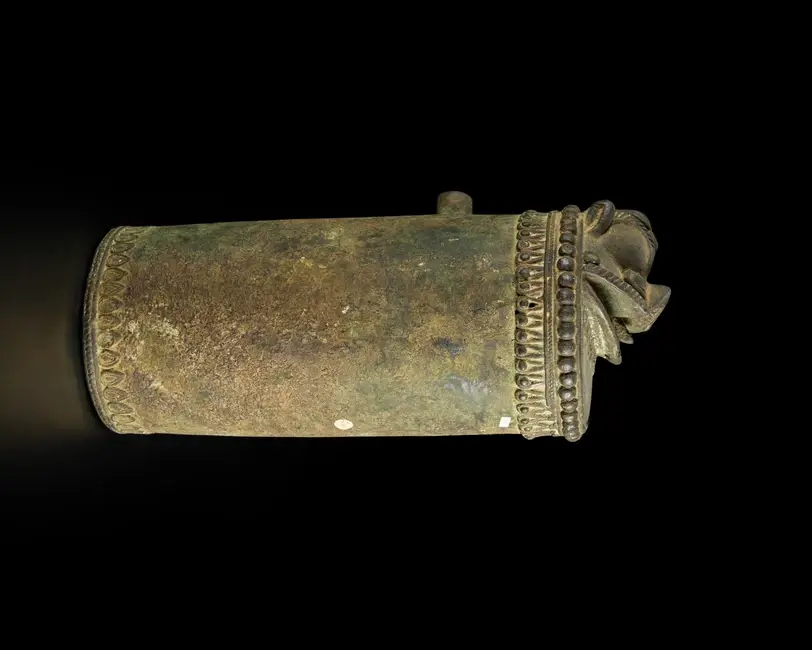 A cylindrical bronze fountain spout or pole finial with a simplified makara head