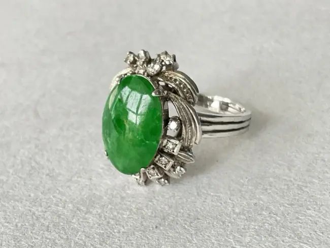 An 18ct white gold ring claw set with central jade cabochon framed