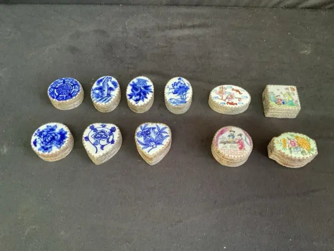 Eleven Chinese silver plated pillboxes, the covers made from fragments