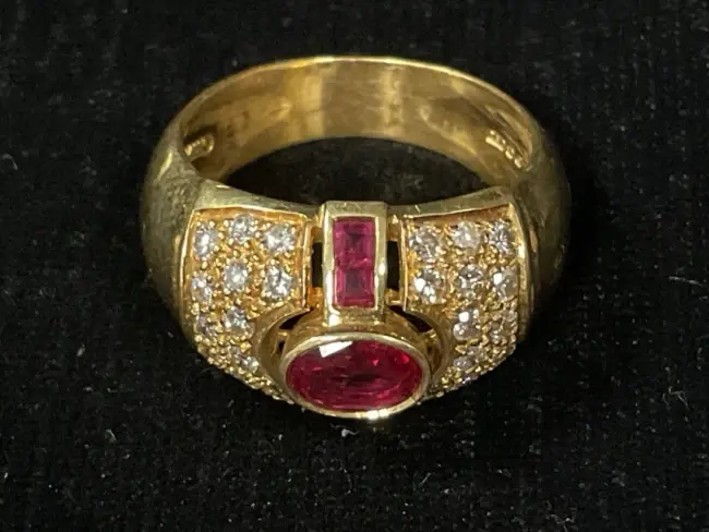 An 18ct gold ring with oval cut and channel set rubies flanked by