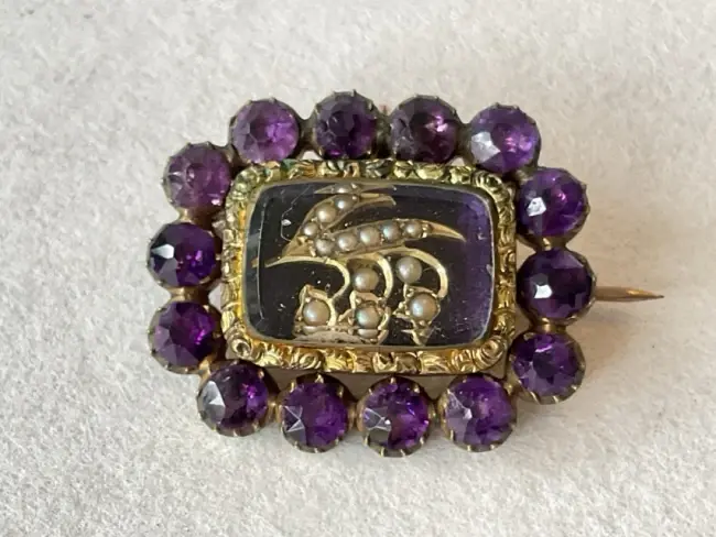 A Victorian gold memorial brooch, with amethysts framing a seed pearl