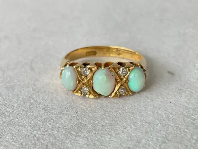 An antique 18ct gold ring set with trilogy of cabochon opals, each