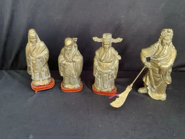 A set of three Chinese cast brass god figures on hardwood stands -
