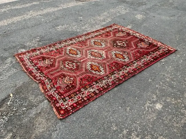 An Afghan wool rug with a pattern of hooked medallions on a red field