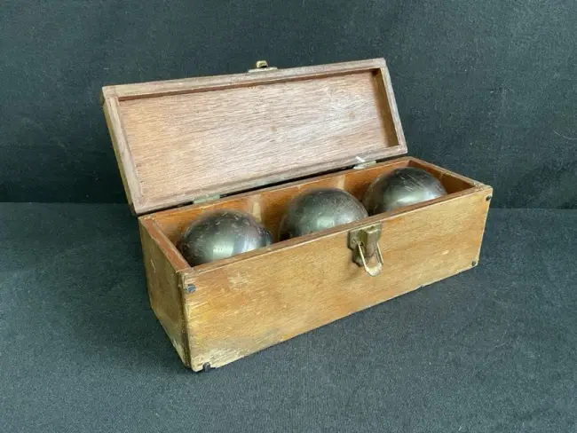 A set of three cast iron French boules, in a rectangular brass handled