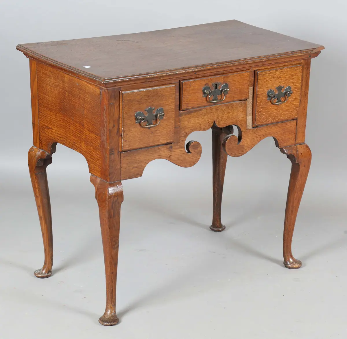 A George III oak lowboy, fitted with three drawers, on cabriole legs