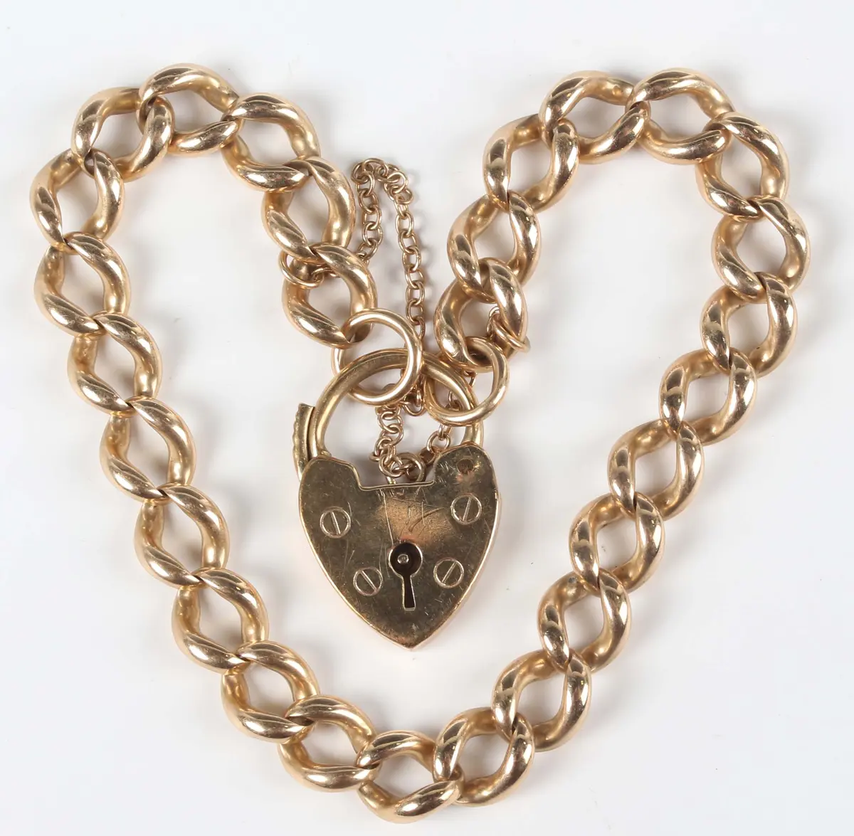 A 9ct gold curblink bracelet on a 9ct gold heart shaped padlock clasp