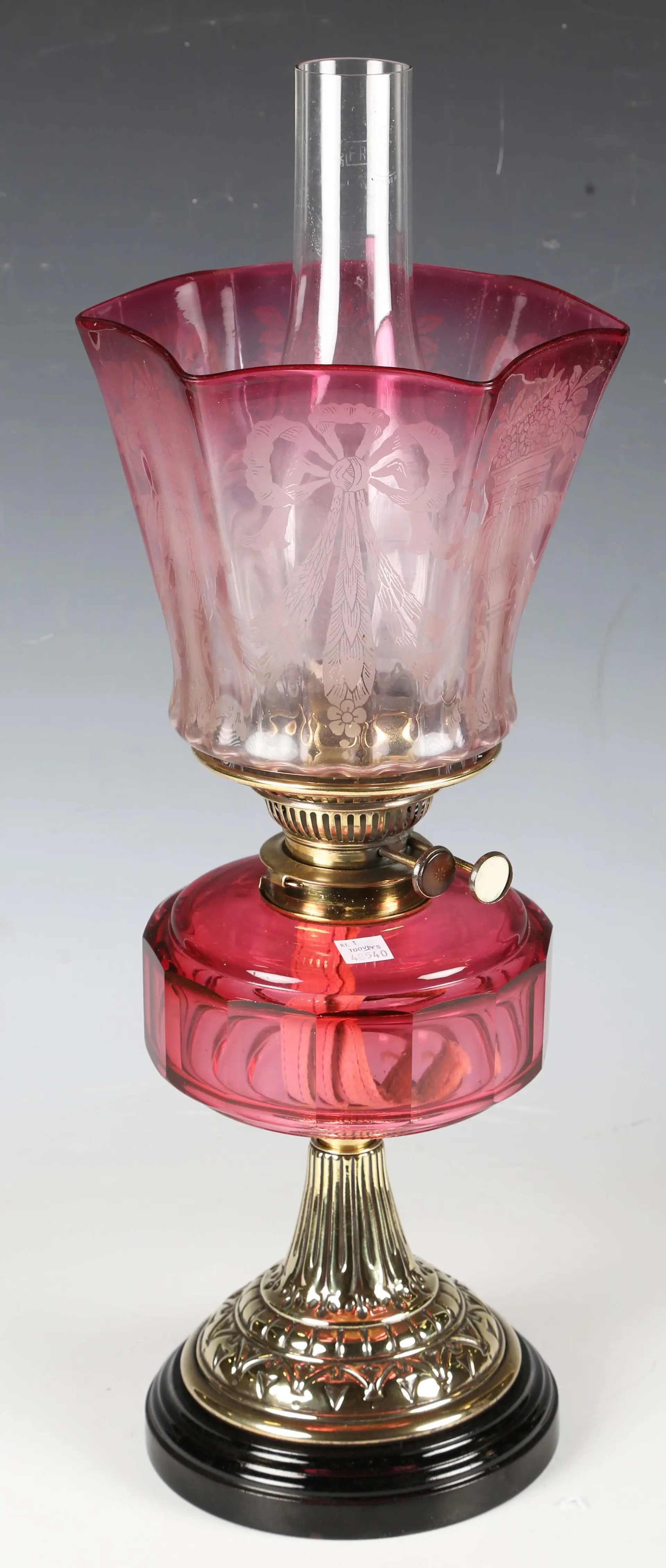 A Victorian brass and cranberry glass table oil lamp with an etched