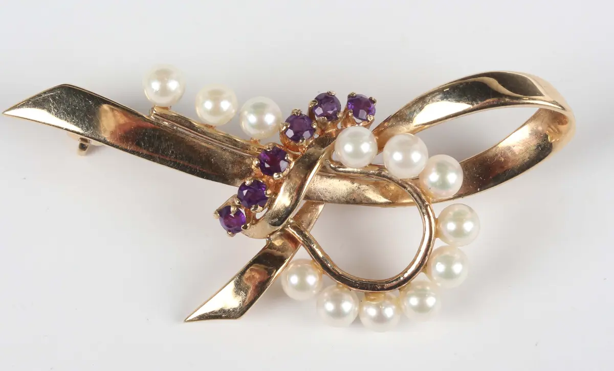 A 9ct gold, amethyst and cultured pearl brooch of stylized tied bow
