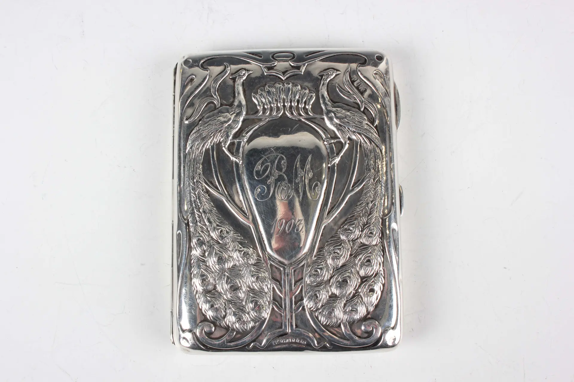 An Art Nouveau silver aide-mémoire, the front embossed with a pair