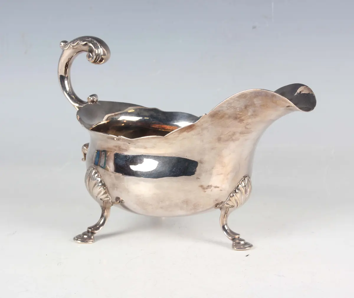 A George III silver sauceboat with shaped rim and foliate capped scroll