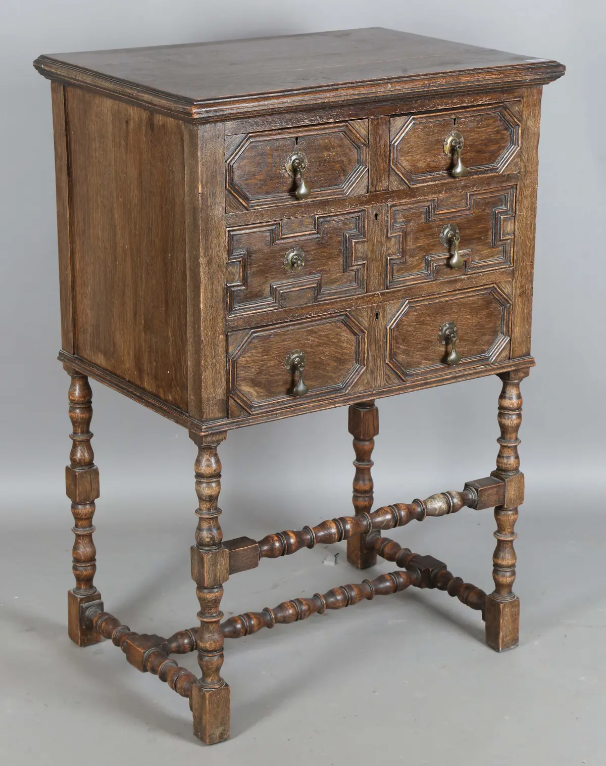 An early 20th century Jacobean Revival oak chest-on-stand, the three