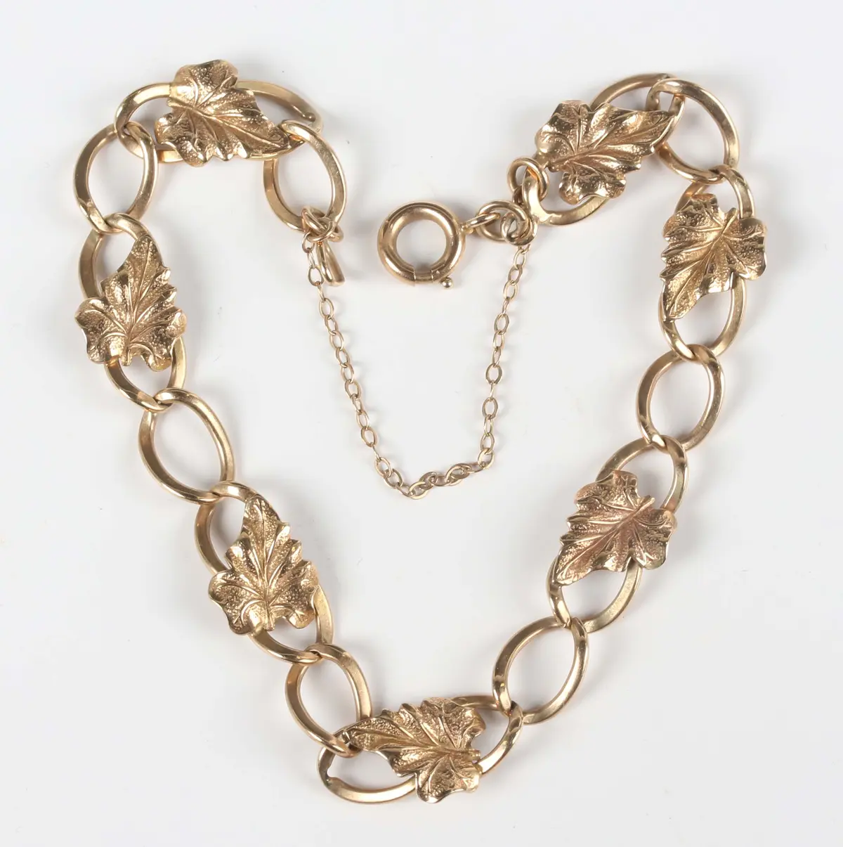 A 9ct gold curblink bracelet, applied with leaf motifs at intervals