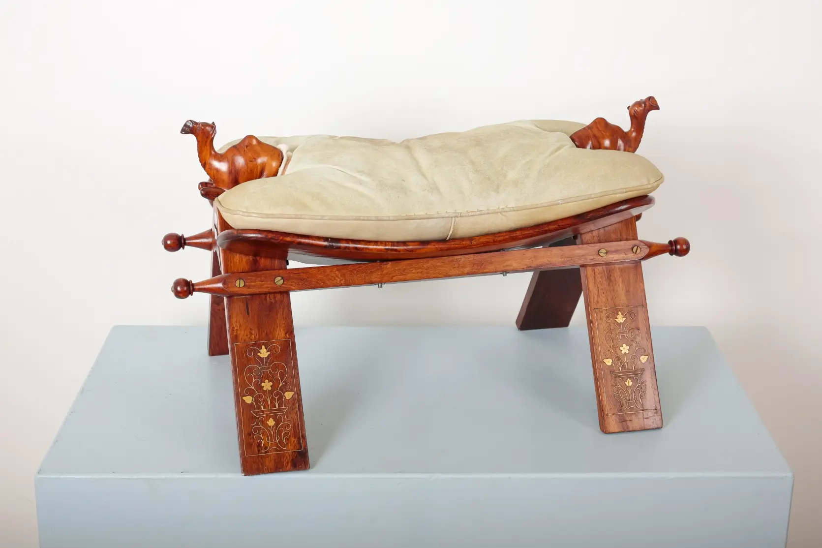 A CARVED WOOD CAMEL SADDLE FOOT STOOL
