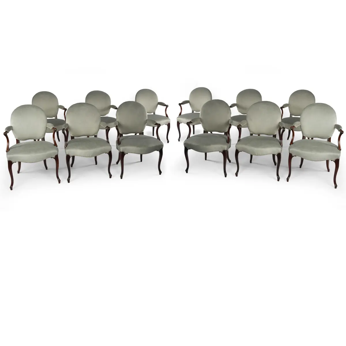 A rare set of twelve George III mahogany open arm chairs in the French