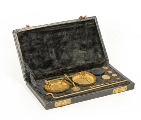Small travel scale with two weighing pans in gilded metal, weights