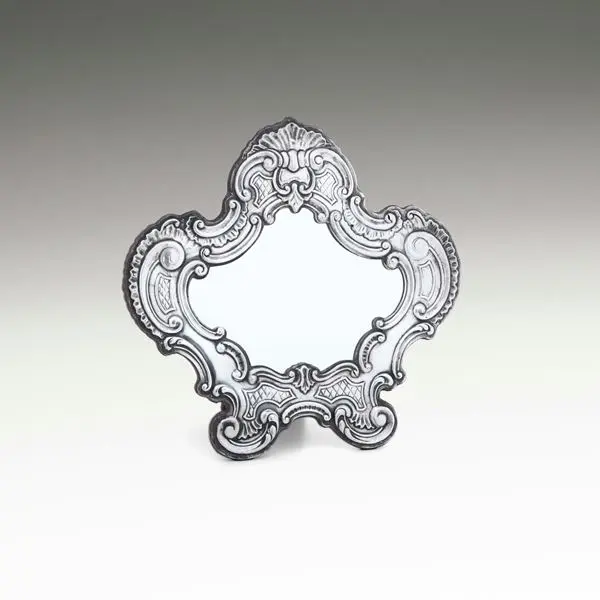 Uno specchio da tavolo con cornice di gusto barocco. Argenteria artistica
