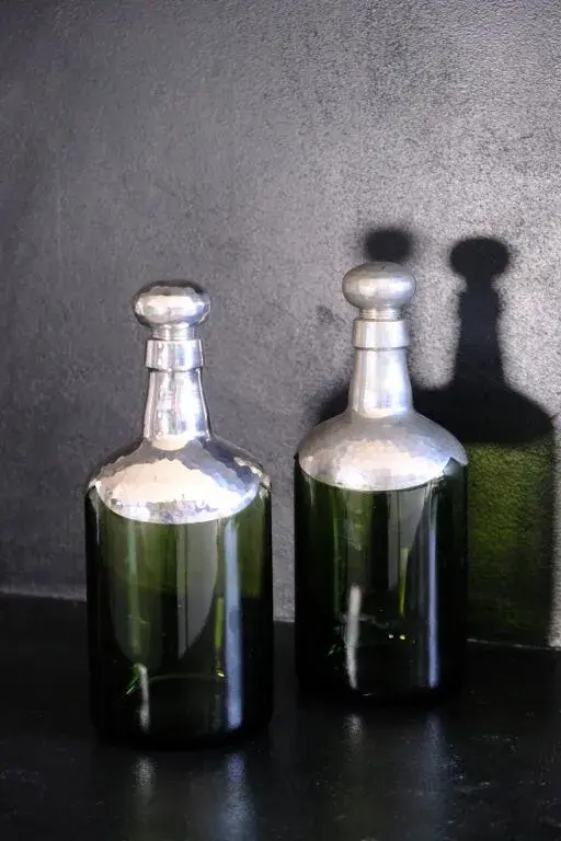 Pair of tinted glass carafes with hammered pewter bases and stoppers.