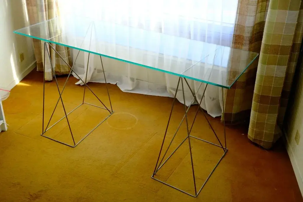 A modernist console table featuring a rectangular glass top resting