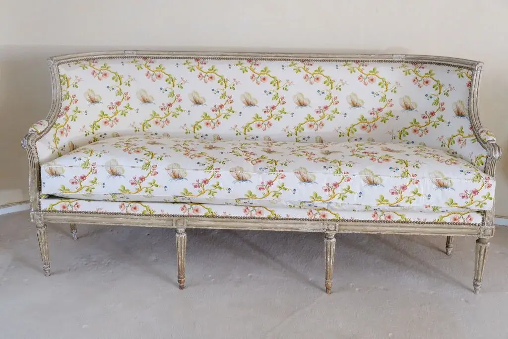 A cream-relacquered, molded-wood sofa supported by nine tapered, fluted