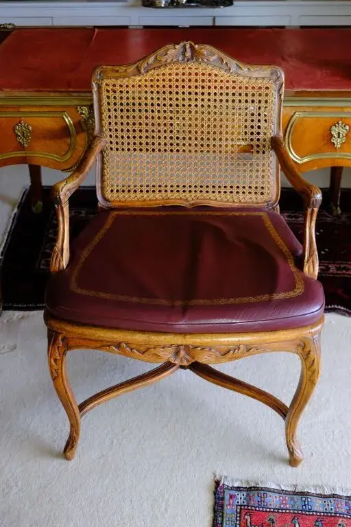 Natural wood cane armchair, carved with acanthus leaves; the curved