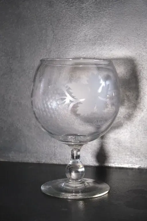 A wine glass made of blown crystal and engraved with grapevine tendrils.