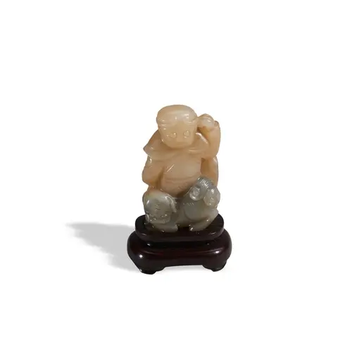 A JADE FIGURE OF A BOY RIDING A LION WITH WOOD STAND, 20TH C...