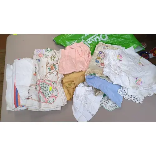 A quantity of embroidered table linens in white and pastel-c...