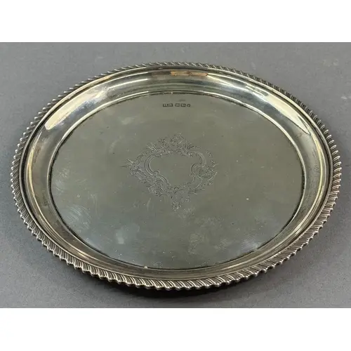 Silver: a circular salver with gadrooned rim and central eng...