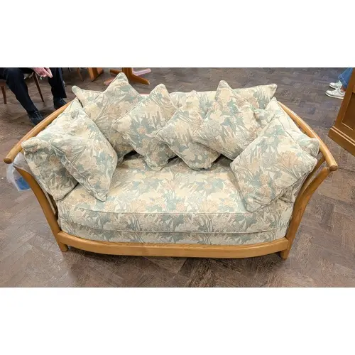 An Ercol blond elm two seater settee with slatted arms and b...
