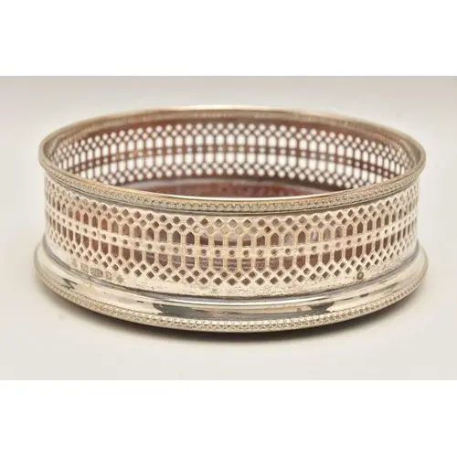 AN ELIZABETH II SILVER BOTTLE COASTER, circular wooden base ...