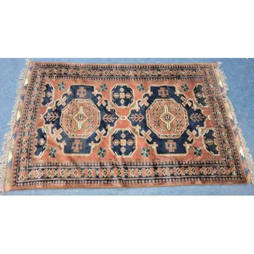 A RED AND BLUE GROUND RUG, with repeating patterns, surround...