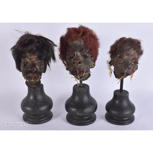 THREE SOUTH AMERICAN TRIBAL HEADS upon later ebonised wood s...