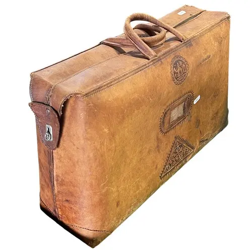 An old eastern carpet bag together with a large tooled vinta...