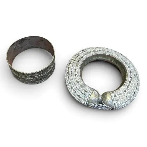 A SILVER TRIBAL BANGLE AND ANOTHER METAL BANGLE Largest 13cm...