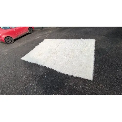 Rectangular cream shag rug with a long, loose pile and woven...