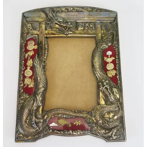 A Chinese white metal frame with embossed dragon decoration ...