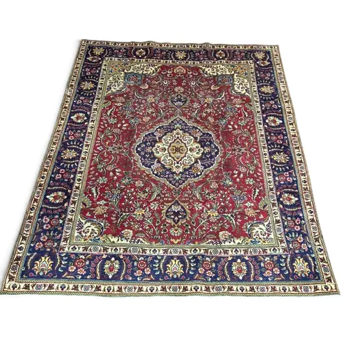 A hand-woven Persian Tabriz carpet, decorated with a traditi...