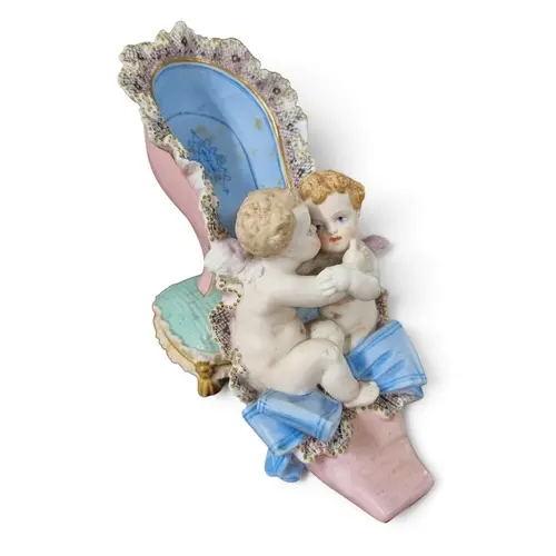 A French Porcelain piece depicting Cherubs sitting in a shoe...