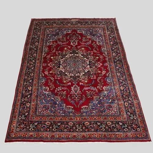 MASHAD CARPET. The deep raspberry field of floral vines arou...