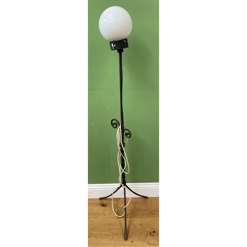 A wrought metal standard lamp with milk glass orb shade