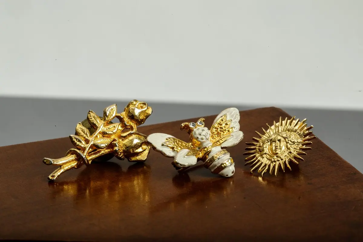 Set of two pins and a gold-plated brooch featuring a beaded - Lot 153