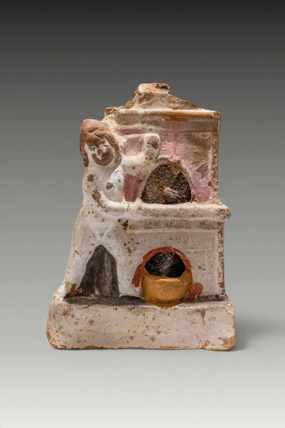 RARE ROMANO-EGYPTIAN PAINTED TERRACOTTA EROS BESIDE AN OVEN