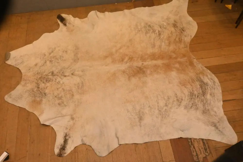 A VINTAGE COWHIDE RUG - SIGNS OF REPAIR (A/F) (234 X 213...